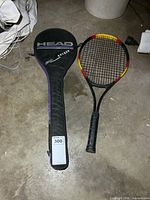 Head squash racket cover lying next to Power Plus tennis racket