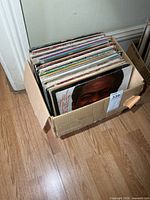Cardboard box containing large stack of LPs