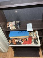 Shot mug, postcard and books on shelf