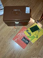Closed brown sewing box, manuals visible