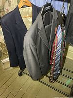 Grey Jones New York suit jacket and pants hung on DKNY hanger beside navy blazer, ties visible