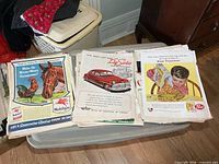 Stacks of loose vintage ads showing Mobilgas horse ad, DeSoto car ad, Post cereal ad