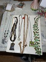 Six necklaces laid out on board showing variety of pendants and chains