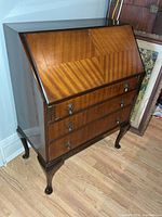 Front view of mahogany secretary desk showing drop-front closed and three drawers