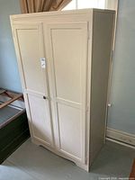 Front view of cream painted wardrobe cabinet showing double doors and missing knob