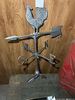 Full view of metal rooster weather vane showing arrow, directional letters and base
