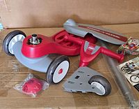 All disassembled scooter parts on box including deck, handlebar, wheels, hardware