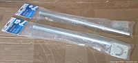 Two packaged zinc closet rods side by side