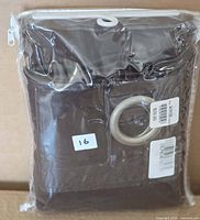 Sealed package showing brown curtain panel with metal grommet visible