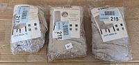 Three factory-sealed Enova Home chair cover packages on cardboard