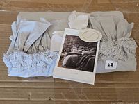 Front view of folded light gray sham with ruffled edges and product card