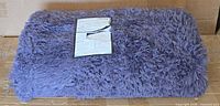 Rolled purple shag rug on box