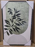 Shrink-wrapped framed canvas print with corner protectors, geometric plant leaf design visible