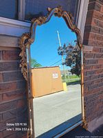Full view of mirror leaning against brick wall