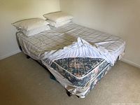 Double mattress with pillows and sheet partially pulled back revealing floral patterned sides