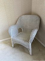 Front angle of white wicker armchair showing weave and curved arms
