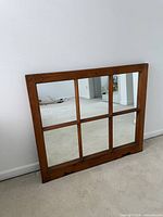 Front view of wooden six-pane mirror leaning against wall