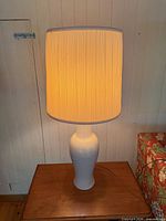 Lamp on side table, illuminated, showing full lamp and shade