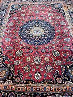 Full view of rug showing red field with navy medallion and borders