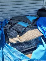 folded grey wicker-pattern vinyl liner with blue interior sections under tarp