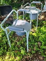 Two portable commode chairs with metal frames and buckets