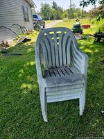 Stacked grey plastic patio chairs on lawn