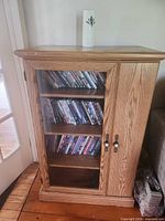 full view of wood media cabinet with glass door, CDs visible on shelves