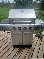 Front view of stainless steel Elite gas BBQ with four knobs and storage cabinet