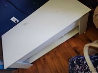 White rectangular coffee table tipped on side showing underside and lower shelf