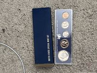 Obverse view of sealed five-coin Special Mint Set alongside original blue box