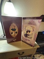 Two boxed Hallmark Barbie dolls on dresser