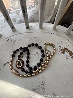 Necklace laid out showing black beads, gold-tone beads, accent pieces