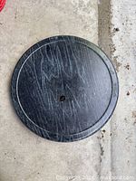 Top view of round black wooden cake stand showing grain and central screw hole