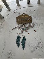All seven earring pairs grouped; card with six pairs and separate teal feather pair visible