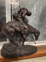 Right side view of sculpture showing rider, horse, rocky base and patina
