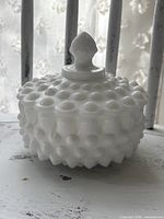 Front view of covered candy dish showing hobnail pattern and finial