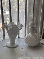 Vase and perfume bottle side by side on table