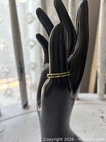 Ring on black display hand showing full band profile and green stones