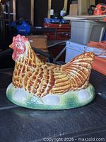 Front angled view of glazed ceramic hen lid showing head and body detailing