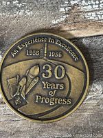 Obverse of coin showing text 'An Experience in Excellence 1956 1986 30 Years of Progress' with rocket and satellite relief