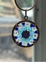 Pendant close-up against blurred background showing millefiori pattern