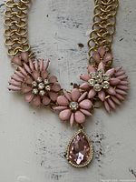 Front view showing pink floral clusters and teardrop pendant