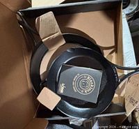 Two cast iron skillets inside original box with tags attached