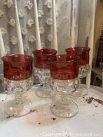 Four ruby rimmed King's Crown goblets on a table
