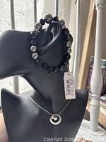 Necklace on bust with bracelet draped over ear area