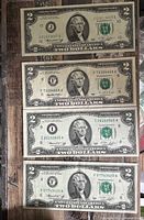 Fronts of four $2 bills showing serials and seals