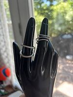 Two eternity bands and two stacked rings on black display hand
