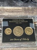 Front of display holder showing three gold-plated coins and inscriptions
