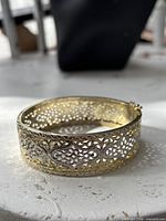 Angled view of bracelet showing filigree work and gold/silver tones