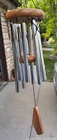 Full view of hanging wind chime showing wood crown, tubes, clapper, and sail